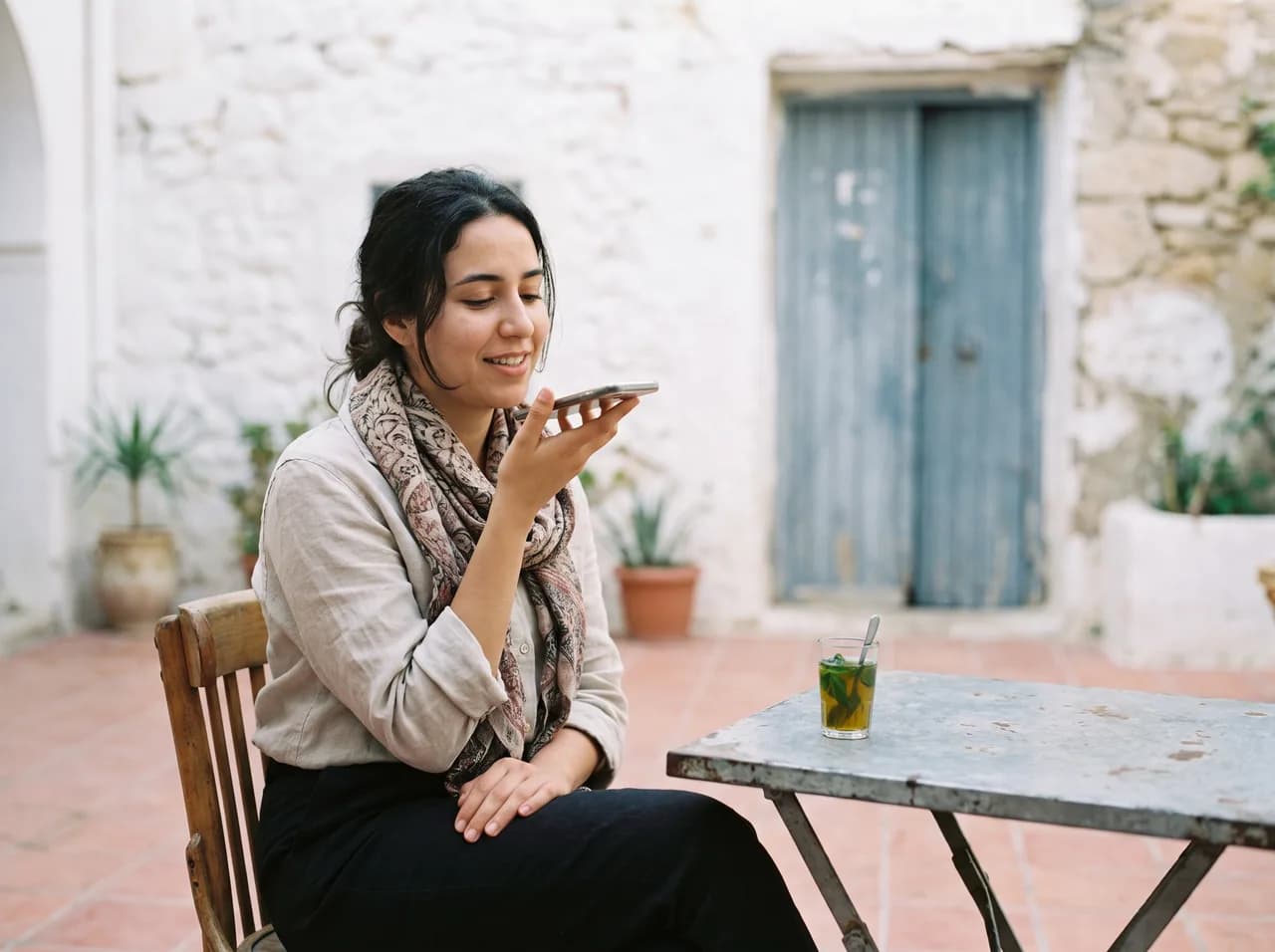 A contributor records a voice sample on her phone in a Tunis courtyard